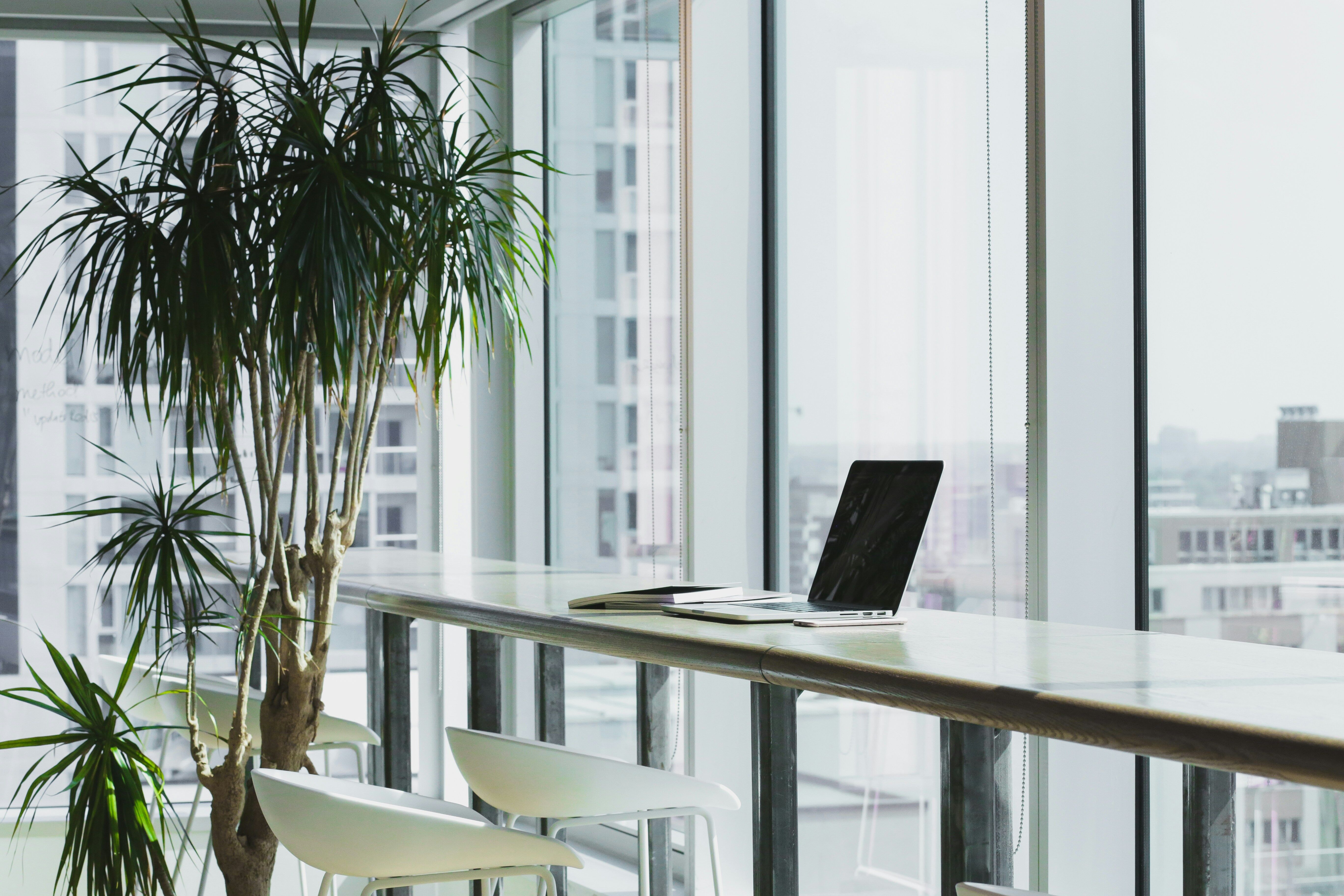 Office space with a laptop on the desk and windows behind it